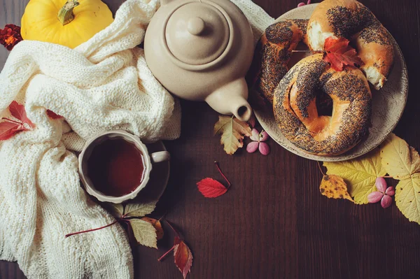 Вид сверху уютный осенний завтрак на столе в загородном доме. Горячий чай, тыквы, бублики и цветы — стоковое фото
