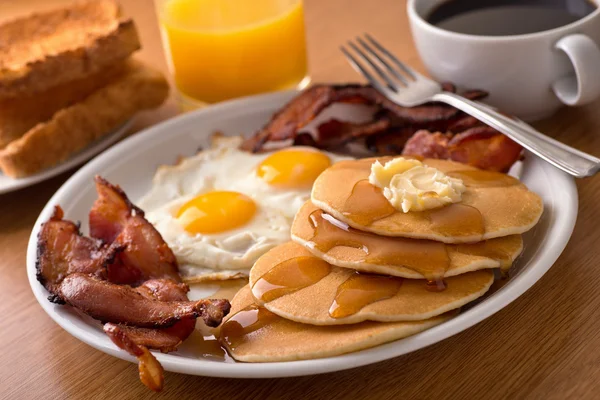 Завтрак с беконом, яйцами, блинами и тостом — стоковое фото