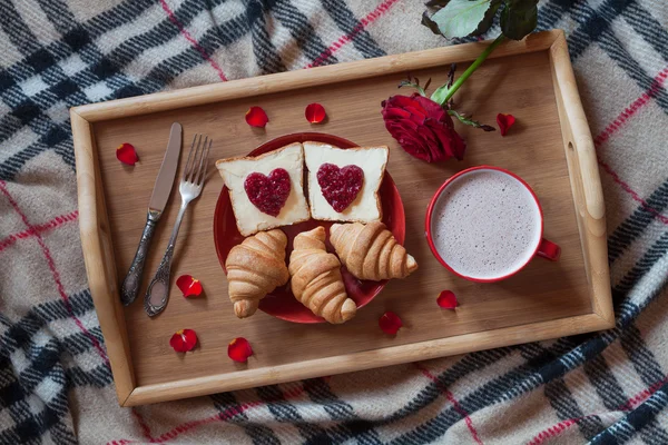 День Святого Валентина романтический завтрак в постель с розовым цветком и лепестками. Тосты, круассаны, горячий шоколад — стоковое фото