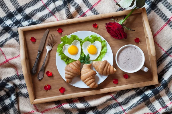 Романтический завтрак в постели с сердцевидным яйца, салат, круассаны, кофе, розы и лепестки на деревянный поднос — стоковое фото